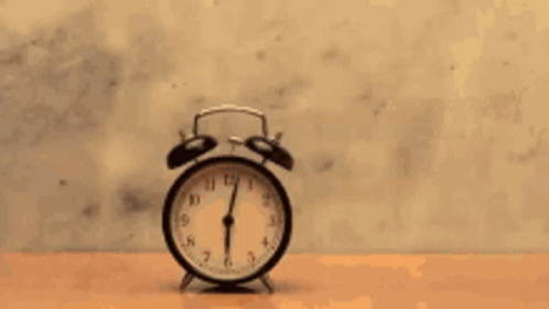 a person is hitting a clock with a hammer on a wooden table .